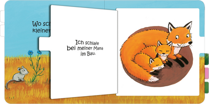 Gezeigt wird eine Innen- oder Zusatzansicht von „Wo schläfst du, kleine Eule?“. Die Illustration zeigt drei Füchse, zwei kleine und ein großer, die gemütlich beieinander liegen. Die Füchse sind in einem warmen Orange gehalten, während der Hintergrund eine sanfte, grüne Wiese mit einem blauen Himmel darstellt. Links steht der Text „Ich schlafe bei meiner Mama im Bau.“ in einfacher, klarer Serifen-Schrift, die gut lesbar ist.