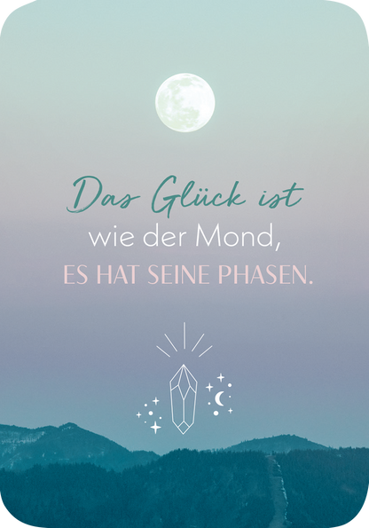 Gezeigt wird eine Innen- oder Zusatzansicht von „Meditations-Mantras“. Die Gestaltung zeigt einen sanften Farbverlauf von hellblau zu lila, im oberen Bereich ist ein voller Mond abgebildet. Die zentrale Botschaft in verschiedenen Schriftarten lautet: „Das Glück ist wie der Mond, ES HAT SEINE PHASEN.“. Unterhalb der Schrift steht ein stilisiertes Kristallsymbol mit Sternen und Mondsilhouetten, das harmonisch in das Gesamtdesign integriert ist.