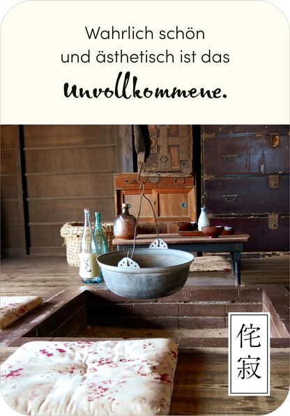 Gezeigt wird eine Innen- oder Zusatzansicht von „Wabi Sabi“. Die Szene ist geprägt von warmen Erdtönen und einem rustikalen, einladenden Ambiente. Im Mittelpunkt hängt eine große, runde Schale über einem tiefergelegten Tisch. Unregelmäßige Holzstrukturen und traditionelle Dekorationselemente unterstreichen den Charakter. Eine stilvolle, schwungvolle Schrift präsentiert das Zitat „Wahrlich schön und ästhetisch ist das Unvollkommene.“ in harmonischem Kontrast zum Hintergrund.