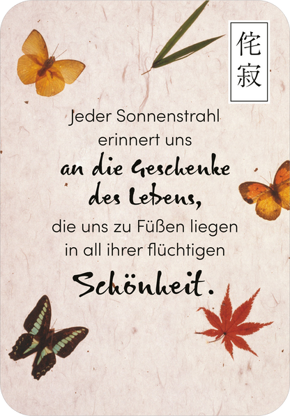 Gezeigt wird eine Innen- oder Zusatzansicht von „Wabi Sabi“. Der Hintergrund ist beige und leicht strukturiert, verziert mit stilisierten, bunten Schmetterlingen in Gelb und Schwarz sowie roten Ahornblättern. In der Mitte des Designs steht der Text in einer gut lesbaren, verspielten Schriftart, die eine sanfte, handgeschriebene Anmutung hat. Die zentrale Botschaft verlieht dem Bild eine nachdenkliche Stimmung und betont die Vergänglichkeit der Schönheit.