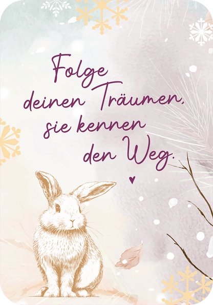 Gezeigt wird eine Innen- oder Zusatzansicht von „Winterzauber für dich“. Die Illustration zeigt einen Hasen in sanften, natürlichen Farben, umgeben von frostigen Schneeflocken und stilisierten Winterelementen. Der Schriftzug „Folge deinen Träumen, sie kennen den Weg“ ist in geschwungener, lila Typografie gestaltet und vermittelt eine inspirierende Botschaft. Die pastellfarbige Hintergrundgestaltung schafft eine warme, einladende Atmosphäre.