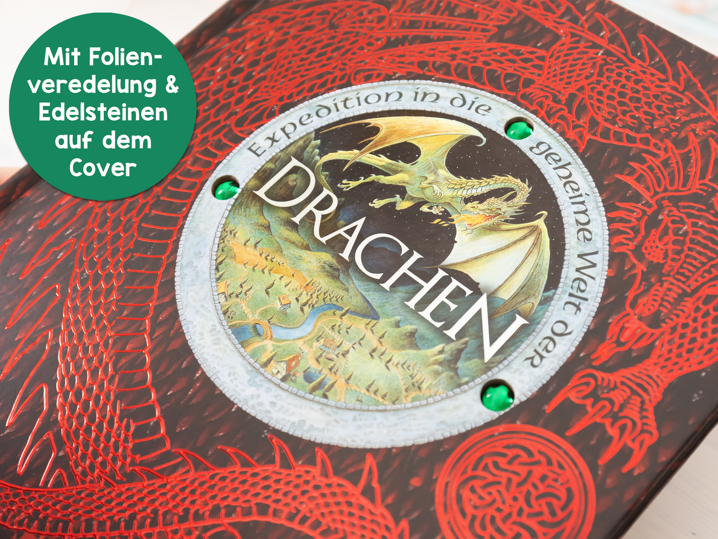 Gezeigt wird eine Innen- oder Zusatzansicht von „Expedition in die geheime Welt der Drachen“. Der Einband zeigt kräftige rote Farben mit einem detaillierten Drachenmotiv in der Mitte. Der Titel „DRACHEN“ ist in großen, geschwungenen Buchstaben in Schwarz hervorgehoben. Die Schriftanordnung wirkt dynamisch und ansprechend. Rund um das Cover sind Folienveredelungen und grüne Edelsteine, die Akzente setzen und dem Gesamtbild einen magischen Charme verleihen.