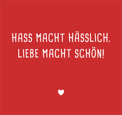 Gezeigt wird eine Innen- oder Zusatzansicht von „Nie wieder ist jetzt“. Der Hintergrund ist in einem kräftigen Rot gehalten. In der Mitte steht der Satz „HASS MACHT HÄSSLICH. LIEBE MACHT SCHÖN!“ in auffälliger, weißer Schrift mit verspielten, handschriftlichen Elementen. Darunter befindet sich ein kleines, schlichtes Herz. Die Typografie vermittelt eine emotionale Botschaft und schafft eine ansprechende, positive Atmosphäre.