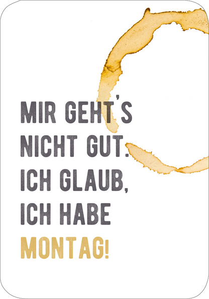 Gezeigt wird eine Innen- oder Zusatzansicht von „Einer von uns beiden ist blöder als ich.“. Der Hintergrund ist weiß, während der Text in verschiedenen Schriftgrößen und -farben gestaltet ist. Die Phrasen „MIR GEHT&#039;S NICHT GUT.“ und „ICH GLAUB, ICH HABE“ sind in dunkler Graufarbe gehalten, während das Wort „MONTAG!“ in kräftigem Gold erscheint. Ein Kaffeefleck in warmen Brauntönen bildet eine kreative, visuelle Umrahmung und dient als Blickfang.