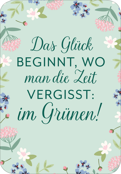 Gezeigt wird eine Innen- oder Zusatzansicht von „Wiesenglück“. Der Hintergrund ist in einem sanften Mintgrün gehalten, umrahmt von blühenden floralen Elementen in Rosa, Blau und Weiß. Im Mittelpunkt steht der große, elegante Schriftzug „Das Glück beginnt, wo man die Zeit vergisst: im Grünen!“, der in einer geschwungenen Schriftart in Dunkelgrün hervorgehoben ist. Die harmonische Farbenkombination und die liebevolle Typografie vermitteln eine fröhliche und einladende Atmosphäre.