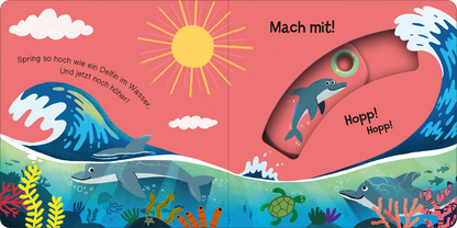 Gezeigt wird eine Innen- oder Zusatzansicht von „Mach mit! Schnipp! Schnapp!“. Die Illustration zeigt einen bunten, wogenden Ozean mit blauen Wellen und einem leuchtend gelben Sonnenmotiv im Hintergrund. Darin sind ein Delfin und eine Schildkröte abgebildet, die zwischen bunten Korallen schwimmen. In kräftigem Rot steht der Text „Mach mit!“ und darunter „Hopp! Hopp!“, die Typografie ist verspielt und einladend, um die Aktivität zur Interaktion zu fördern.
