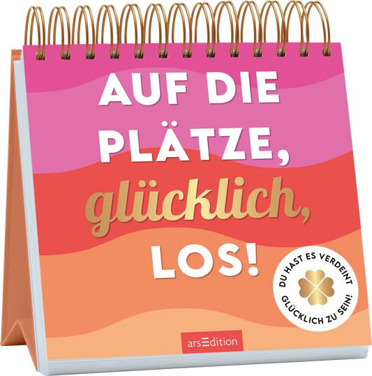Das Buchcover zeigt eine spiralförmige Bindung mit leuchtend bunten Farbverläufen in Pink- und Orangetönen, die eine fröhliche Atmosphäre schaffen. In der Mitte prangt der Titel „AUF DIE PLÄTZE, glücklich, LOS!“ in einer großen, weißen und goldenen Schrift. Auf der unteren rechten Seite befindet sich ein weißes Label mit der Aufschrift „DU HAST ES VERDIENT, GLÜCKLICH ZU SEIN!“. Ganz unten mittig steht der Logoschriftzug von arsEdition.