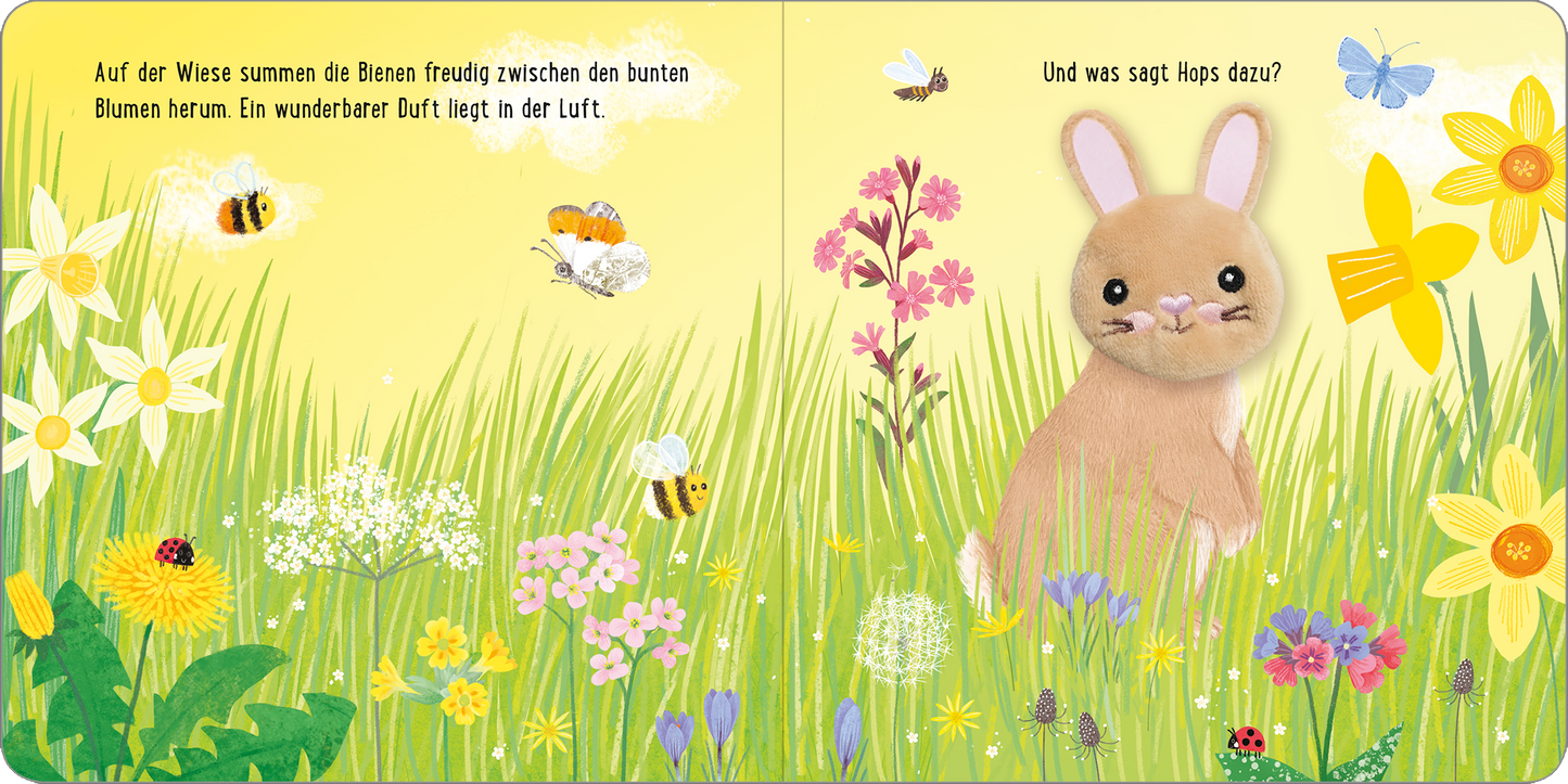 Gezeigt wird eine Innen- oder Zusatzansicht von „Meine sprechende Fingerpuppe: Hops Hase“. Die Illustration zeigt eine blühende Wiese mit bunten Blumen in Gelb, Lila, Rosa und Weiß. In der Mitte sitzt ein niedlicher Hase mit großen Ohren in sanftem Braunton. Um ihn summen fröhliche Bienen. Die Schrift ist klar und kindgerecht, mit einer verspielten Anordnung auf der Seite. Die Gesamtgestaltung vermittelt eine fröhliche, einladende Atmosphäre.