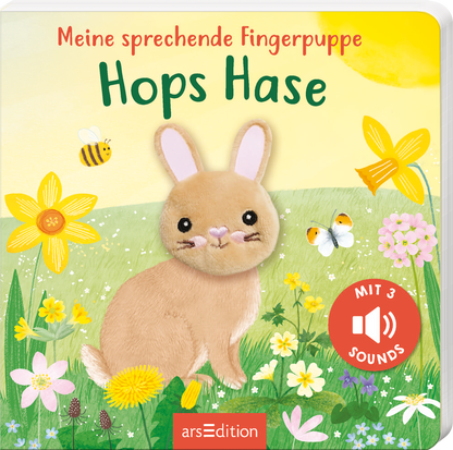 Das Buchcover zeigt den Titel „Hops Hase“ in grüner, handschriftlicher Schrift über einem niedlichen, plüschigen Hasen mit großen Ohren und einem freundlichen Gesichtsausdruck. Umgeben ist der Hase von bunten Frühlingsblumen und fliegenden Insekten, was eine fröhliche, lebendige Atmosphäre schafft. In der unteren rechten Ecke befindet sich ein roter Button mit der Aufschrift „MIT 3 SOUNDS“. Ganz unten mittig steht der Logoschriftzug von arsEdition.