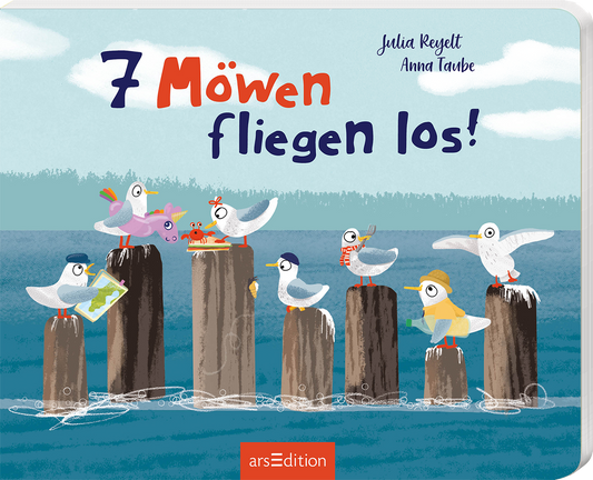 Das Buchcover zeigt eine fröhliche Illustration mit sieben verschiedenen Möwen, die auf Holzpollern am Wasser sitzen. Die Möwen sind bunt und tragen lustige Accessoires wie Hüte und Schals. Der Titel „7 Möwen fliegen los!“ ist in großen, verspielten Buchstaben dargestellt, wobei die Zahlen deutlich hervorgehoben sind. Die Farbpalette ist hell und einladend, mit Blautönen für das Wasser und einem klaren Himmel. Oben links sind die Autorennamen Julia Reylett und Anna Taube zu finden....