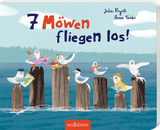 Das Buchcover zeigt eine fröhliche Illustration mit sieben verschiedenen Möwen, die auf Holzpollern am Wasser sitzen. Die Möwen sind bunt und tragen lustige Accessoires wie Hüte und Schals. Der Titel „7 Möwen fliegen los!“ ist in großen, verspielten Buchstaben dargestellt, wobei die Zahlen deutlich hervorgehoben sind. Die Farbpalette ist hell und einladend, mit Blau- und Grüntönen für das Wasser und einem klaren Himmel. Oben links sind die Autorennamen Julia Reylett und Anna Taube...