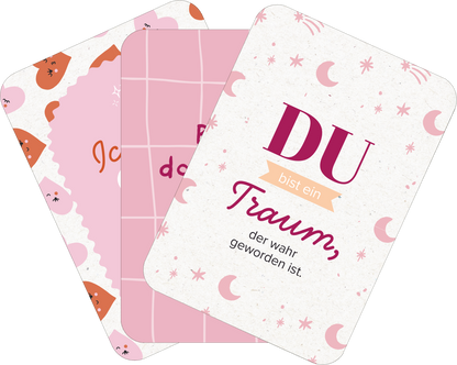 Gezeigt wird eine Innen- oder Zusatzansicht von „50 ungewöhnliche Liebeserklärungen“. Die Karteikarten sind in sanften Rosa- und Pastelltönen gehalten. Auf einer Karte steht in großen, pinken Buchstaben „DU“, gefolgt von „bist ein Traum, der wahr geworden ist“ in einer eleganten Schrift. Eine andere Karte zeigt ein Gittermuster in Rosa mit kleinen, verspielten Illustrationen. Die verschiedenen grafischen Elemente und warmen Farben verleihen dem Design eine freundliche und...