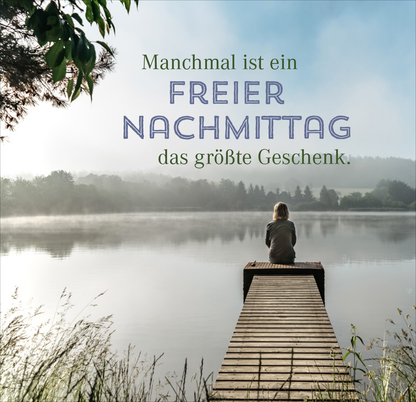 Gezeigt wird eine Innen- oder Zusatzansicht von „Nimm dir Zeit für Gemütlichkeit“. Im Vordergrund sitzt eine Person auf einem Holzsteg und blickt auf einen ruhigen See, der von sanften, grünen Hügeln umgeben ist. Die Farben sind überwiegend natürlich, mit sanften Grüntönen und einem blauen Himmel. Der Text „Manchmal ist ein FREIER NACHTMITTAG das größte Geschenk.“ verwendet eine Mischung aus klarer, eleganter Typografie und einer verspielten Schriftart, die den ruhigen,...