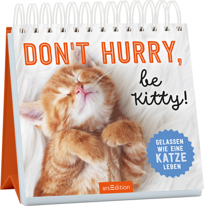 Auf dem Cover ist ein schlafendes, orangefarbenes Kätzchen mit geschlossenen Augen zu sehen, das eine entspannte Pose einnimmt. Der Hintergrund ist hell und weich gestaltet. Der Titel „DON'T HURRY, be KITTY!“ ist in einer großen, orangefarbenen Schrift platziert, während der Untertitel „GELASSEN WIE EINE KATZE LEBEN“ in einer blauen, runden Auszeichnung hervorgehoben wird. Ganz unten mittig steht der Logoschriftzug von arsEdition.