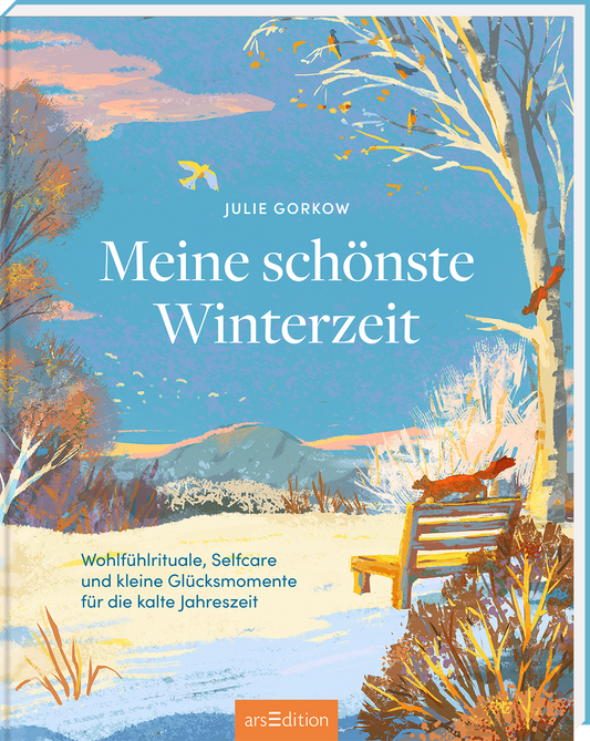 Das Buchcover zeigt eine sanfte Winterlandschaft in hellen Blautönen, mit schneebedeckten Bäumen und einem ruhigen Himmel. In der Mitte sitzt eine Holzbank, umgeben von bunter Natur. Der Titel „Meine schönste Winterzeit“ von Julie Gorkow hebt sich in klarer, eleganter Schrift hervor. Darunter steht der Untertitel „Wohlfühlrituale, Selfcare und kleine Glücksmomente für die kalte Jahreszeit“. Ganz unten mittig steht der Logoschriftzug von arsEdition.
