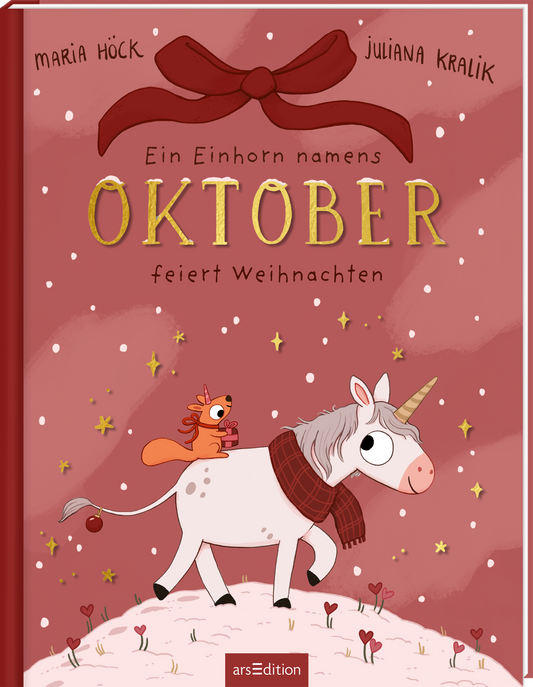 Rosa-rot getöntes Cover mit großen goldenen, reliefartig wirkenden Großbuchstaben „OKTOBER“, darüber rote Schleife. Oben links „Maria Höck“, oben rechts „Juliana Kralik“. Titelzeile „Ein Einhorn namens“ sowie Untertitel „feiert Weihnachten“ in handschriftlicher, dunkler Typografie. Mitte weißes Einhorn mit rotem Schal und Horn, auf dem Rücken sitzt ein kleines Eichhörnchen mit Geschenk, umgeben von goldenen Sternpunkten und Schneeflocken, warme, verspielte...