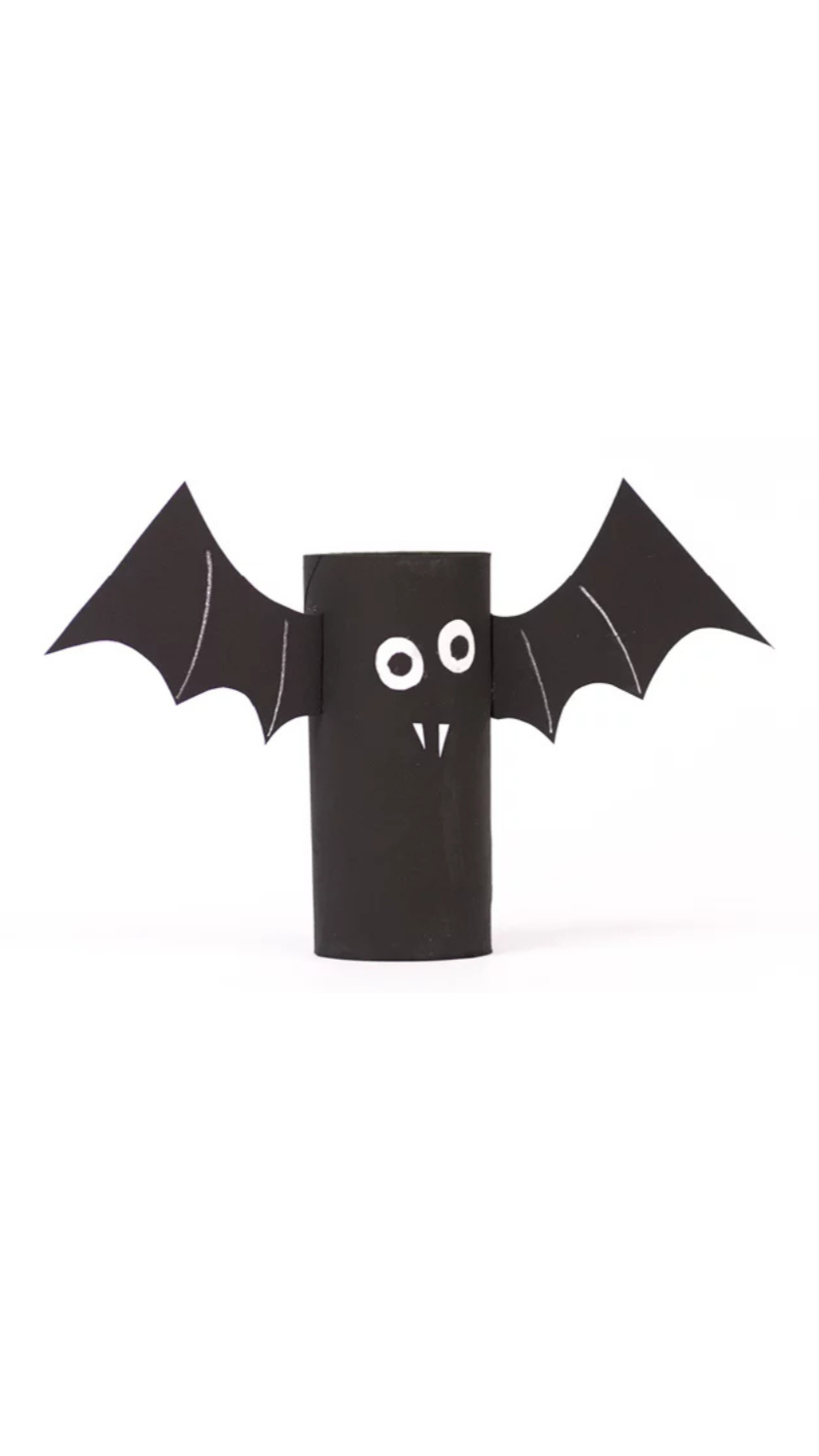 Selbstgebastelte Fledermaus aus einer schwarzen Papprolle mit Flügeln aus schwarzem Papier, weißen Augen und kleinen weißen Vampirzähnen. Die Bastelarbeit steht aufrecht vor einem weißen Hintergrund.