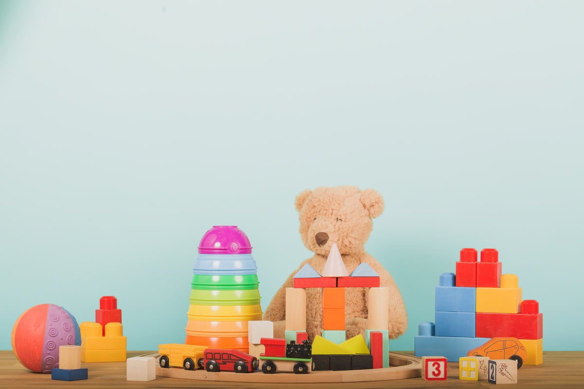 Verschiedenes Spielzeug aus Holz oder Plastik vor hellblauem  Hintergrund
